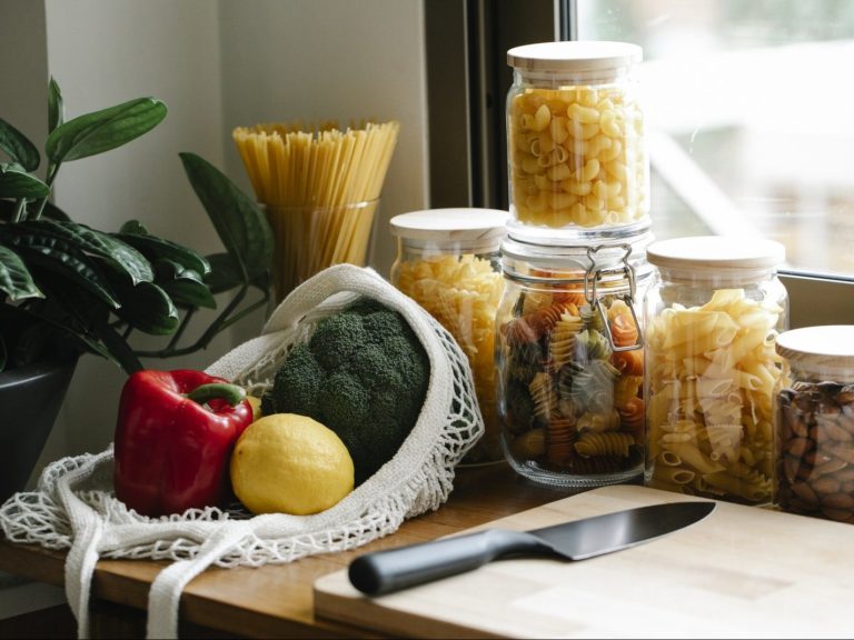 Assorted vegetables placed on counter near jars with pasta