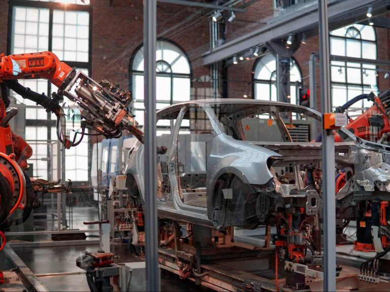 gray vehicle being fixed inside factory using robot machines