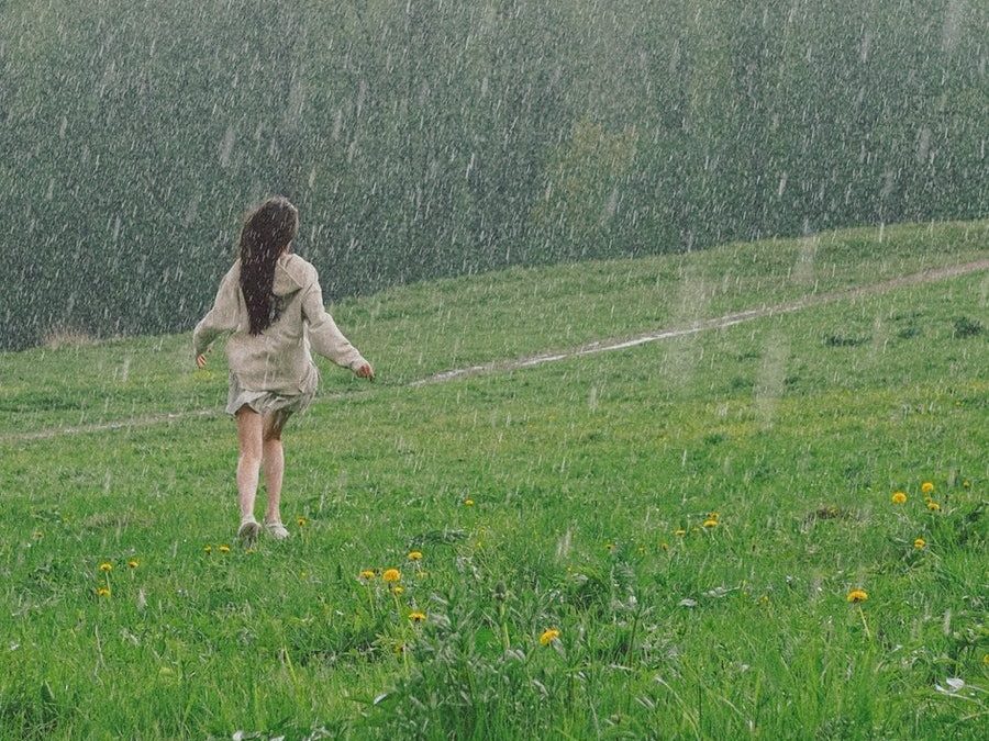 Woman Enjoying The Rain Outside A Grass Field
