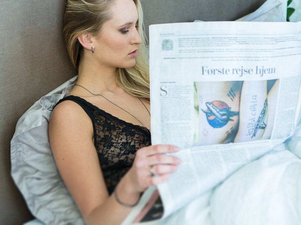woman wearing black chemise reading newspaper