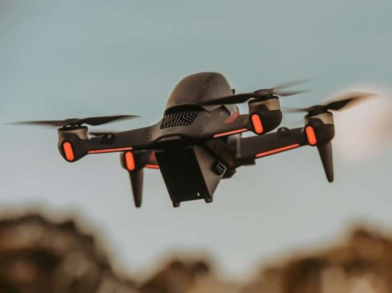 gray and orange drone flying in mid air during daytime